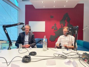 business professionals at an oval table with podcast equipment