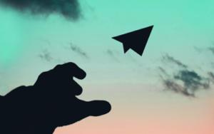 silhouetted hand after launching a paper aeroplane