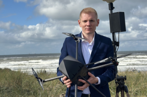 space business entrepreneur holding robotic aerial scanner on a beach