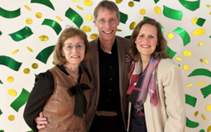 Three people stood in front of a wall with patterned design