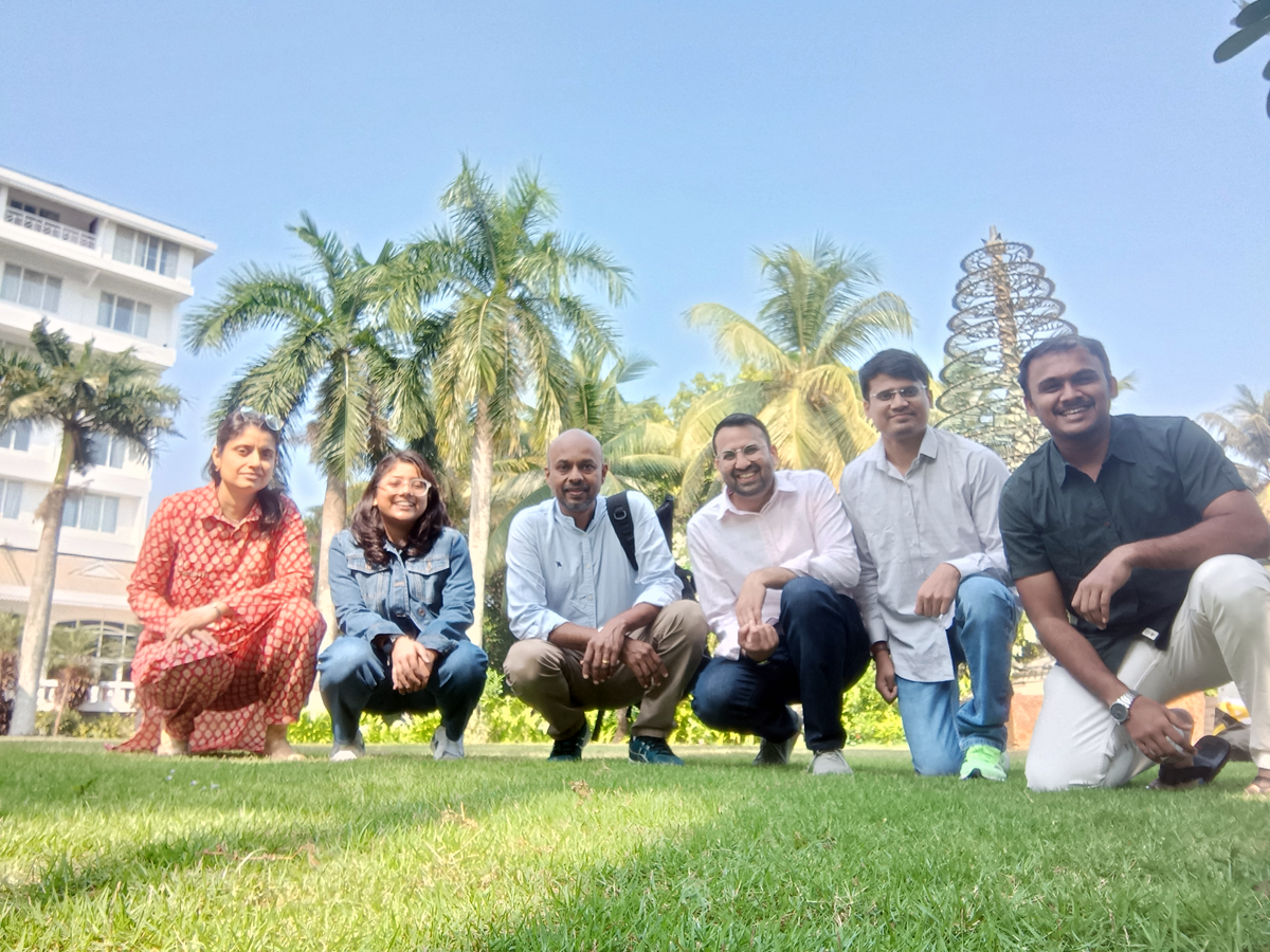 team of people smiling in a park under blue sky