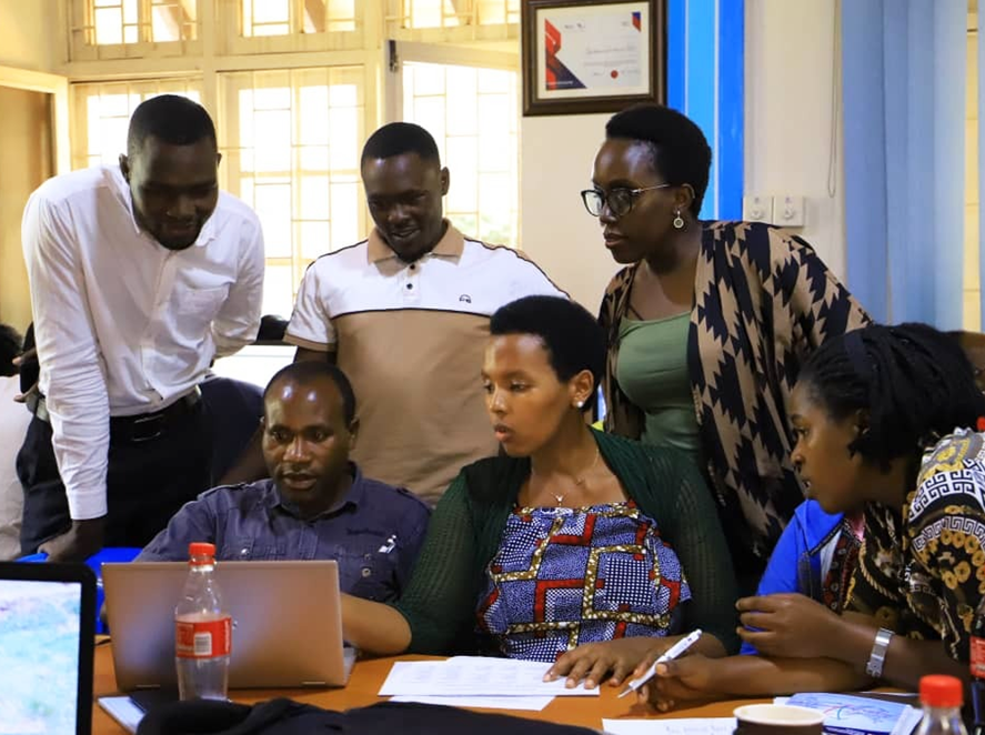 group of people sitting around a laptop 