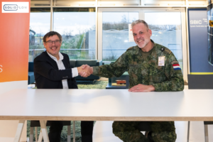 space business and military professionals sit behind a desk signing contract